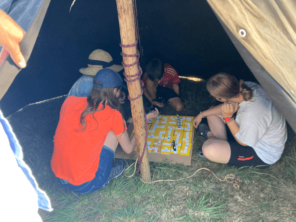 eine Gruppe verschiebt ihre Spielfigur in einem Labyrinth aus Holzteilen