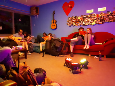 Pfadfinder sitzen um farbige Scheinwerfer und spielen Gitarre